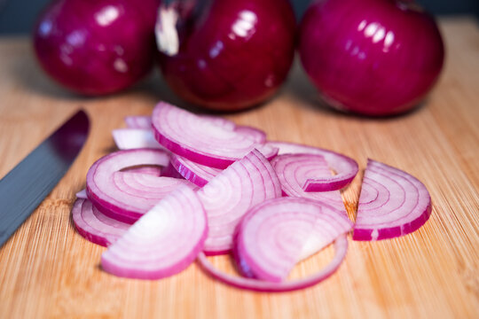 Red onions on a cutting board, sliced with a kitchen knife. Contains vitamin C and fiber., vegetables, vegatarian food, healthy lifestyle, fresh, raw food.