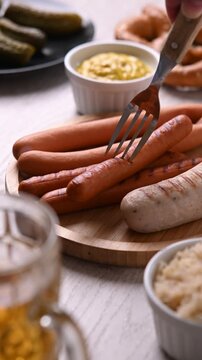 Traditional Oktoberfest food on white wooden table. Fork piercing a frankfurter sausage