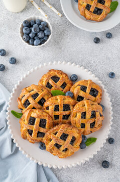 Homemade blueberry hand pies or mini tarts with milk on a concrete background.