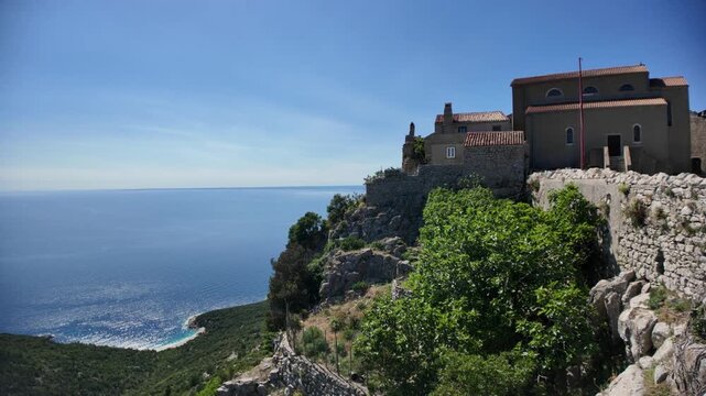 Lubenice medieval village buildings high on a cliff offering panoramic views of Adriatic Sea and Sveti Ivan beach below, representing ancient heritage and Croatian tourism of Cres Island in Croatia