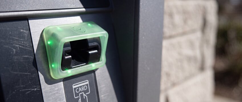 Atm card reader slot integrated into modern metal terminal with glowing green led status lights for secure transaction access.