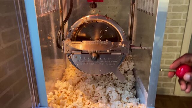 Vintage style popcorn machine kettle with popped kernels inside.