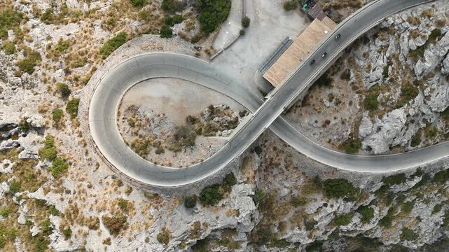 Aerial top down static view of three motorbikes driving on famous Nus de Sa Calobra tie knot loop mountain road in Mallorca Spain