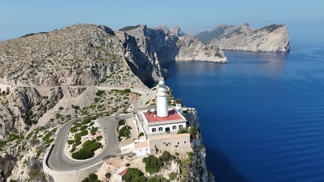 Aerial orbit shot counter clockwise around Cap de Formentor lighthouse revealing dramatic cliffs and sea in Mallorca