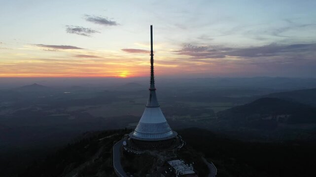 Aerial view of Jested Tower standing on the mountain peak during a golden sunset in Liberec, Liberecky kraj, Czechia.