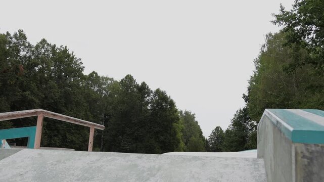 A mature man jumping onto an inclined ramp and riding away on aggressive inline skates at an outdoor skatepark