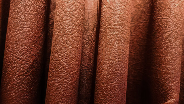 Close-up shot of elegant brown fabric drapes with subtle textured patterns, creating graceful vertical folds and rich, warm shadows.