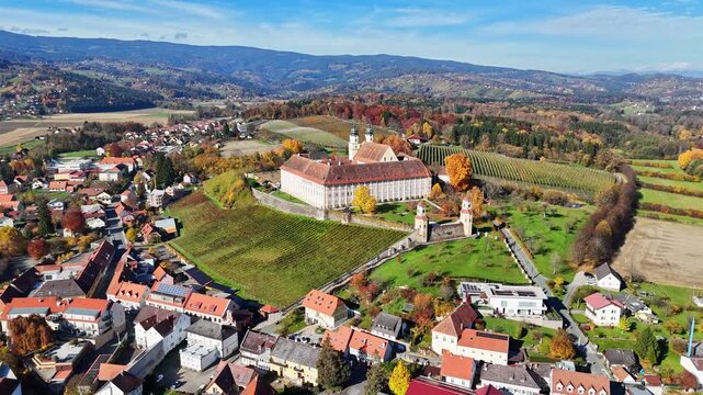 Aerial view of the historic Schloss Stainz castle surrounded by lush vineyards and rolling hills in the Weststeiermark region of Stainz, Styria, Austria.