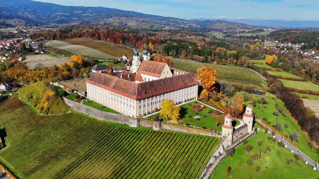 Aerial view of Schloss Stainz surrounded by lush vineyards and autumn foliage in the Weststeiermark region of Stainz, Styria, Austria.