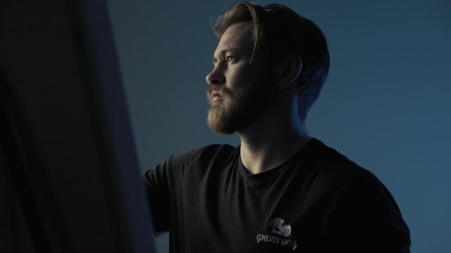 A male artist paints on a canvas. Medium shot. Moody. High quality 4k footage.