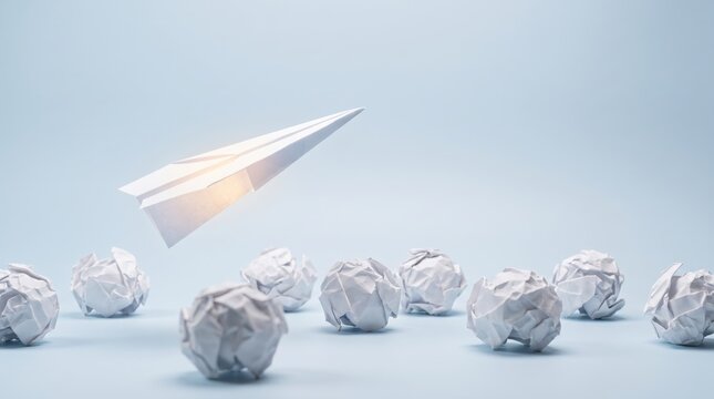 White paper airplane flying above crumpled paper balls on blue background