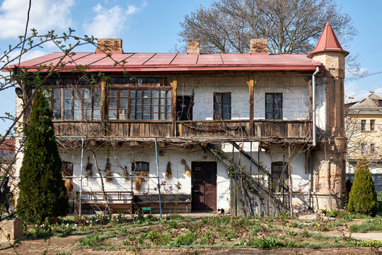 Old rustic house with wooden balcony and garden under blue sky