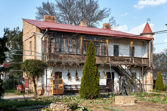 Old rustic house with wooden balcony and garden under blue sky