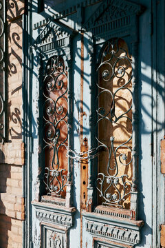Vintage double wooden door with ornate ironwork chained and weathered facade