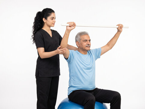 premium indian physiotherapist assisting senior man with shoulder flexion rehabilitation using pvc therapy stick isolated on white background for orthopedic healthcare