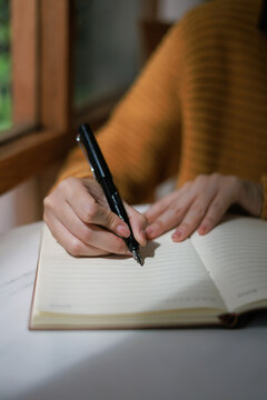 Close up of a hand holding a fountain pen writing in a lined notebook