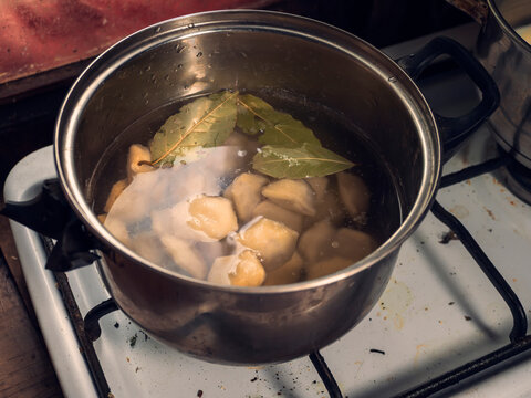 Dumplings in a pot of hot boiling water with bay leaf. Popular Russian dish. Cooking simple tasty food. Fine fast food meal with different flavour.