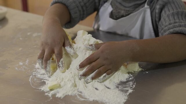 Indigenous child kneading flour on a metal table to make bread; malnutrition syndrome