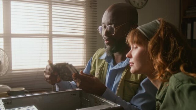 African American man explaining computer hardware to Caucasian young adult woman before installing graphics card. Ideal for IT support training and computer assembly tutorials