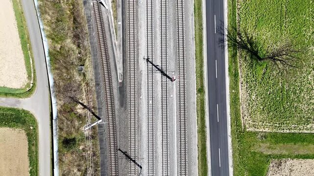 Aerial view of Koralmbahn railway tracks running parallel to a paved road through the rural landscape of Deutschlandsberg, Steiermark, Austria.