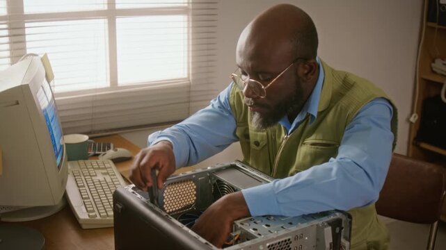 African American technician unscrewing desktop computer case and examining graphics card Perfect for promoting IT support services or computer repair business advertising