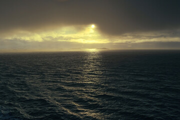 Fototapeta premium Golden sunlight breaking through clouds over the sea