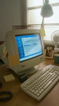 Vertical shot of retro computer monitor displaying vintage software interface on wooden desk. Footage suits nostalgic technology marketing or historical computing projects
