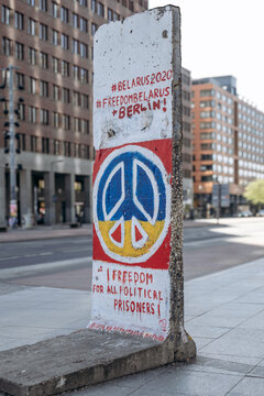 Berlin, Germany - April 23, 2026: Preserved Berlin Wall segment featuring peace symbol and pro-democracy graffiti at the Berlin Wall Exhibition near Potsdamer Platz.