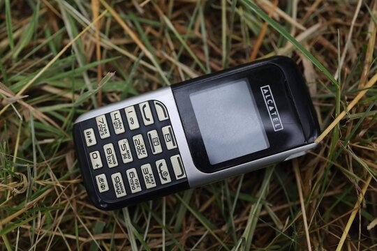 LVIV, UKRAINE - July 03, 2026: Alcatel Old mobile phone lying in grass