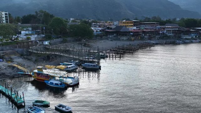Aerial view of Lake Atitlan with wooden piers and colorful boats docked along the shore in Santiago Atitlan, Solola Department, Guatemala.