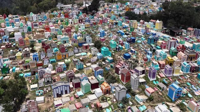 Aerial view of the vibrant, colorful mausoleums and tombs in the historic Chichicastenango cemetery, set against a lush hillside in Chichicastenango, Quiche Department, Guatemala.