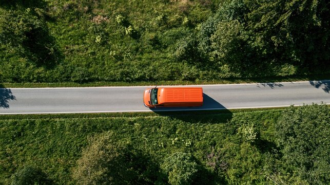 Growth journey with an orange van driving on a narrow road through lush green countryside seen from above