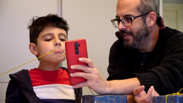 Father and son taking funny selfies during Christmas gift wrapping