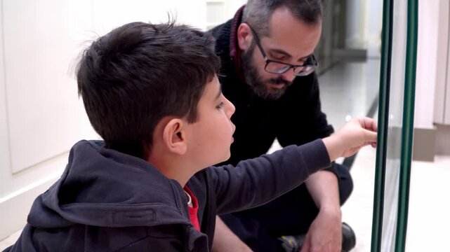Boy helping his father decorate the glass door for Christmas