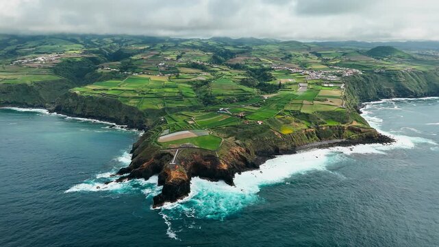 Aerial view of a rural peninsula with patchwork farmland, Atlantic Ocean on both sides. Agricultural coastal landscape of Sao Miguel Island