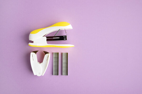 Stapler and staples on purple background
