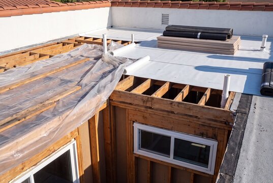 Flat roof under construction with exposed wooden joists and white membrane