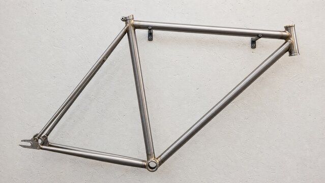 Retro metal bicycle frame made of steel pipes hanging on a white wall