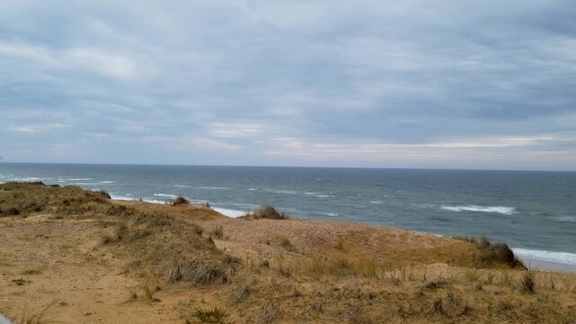 Coastal landscape showing sandy dunes and ocean waves under a cloudy sky, with gradual changes in perspective across three frames capturing the serene beach environment
