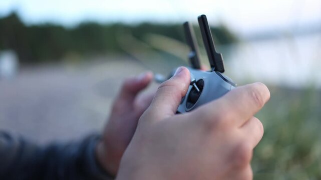 Close up of hands operating a drone remote controller with fingers moving the joysticks during flight control highlighting precise piloting and modern technology