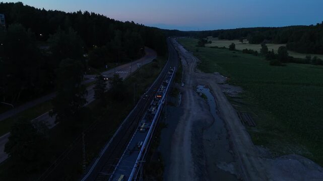 Drone aerial footage of a passenger train moving through a rural landscape with railway tracks bordered by forests and green fields