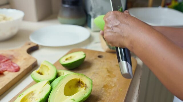 Peeling a fresh ripe avocado with a kitchen knife, close up