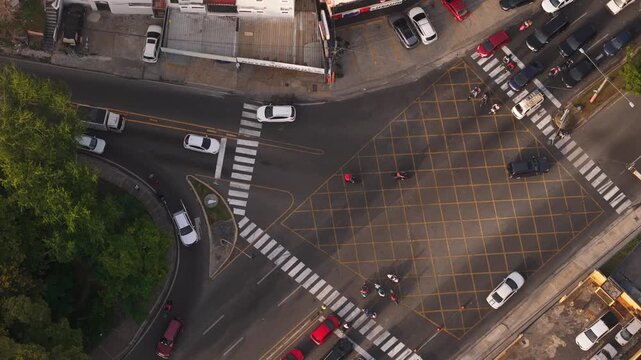 Overhead aerial view of urban traffic navigating a yellow box junction near commercial buildings