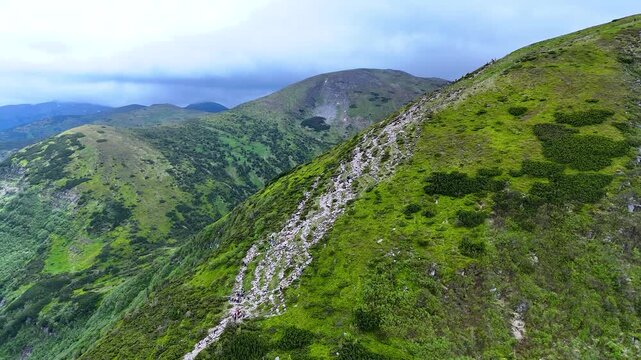 Mass ascent of tourists to Goverla mountain, the highest peak of the Ukrainian Carpathians. Soil erosion around the trail on the mountain slope is a consequence of mass tourism. Concept of travel.
