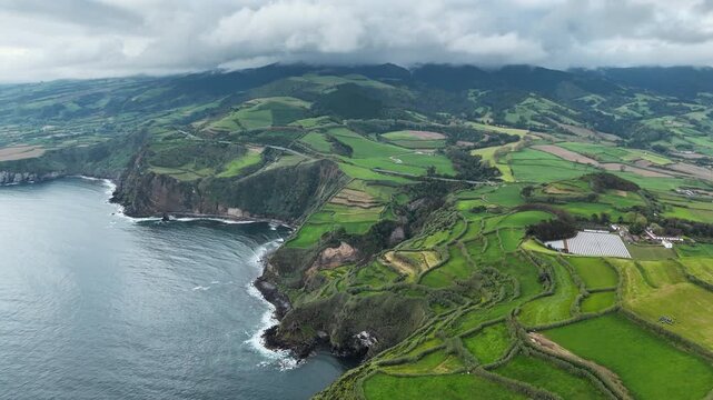 Mosaic farmland pattern meeting rocky shore on volcanic coast of Azores Islands. Aerial view