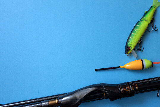 A sleek fishing rod, bright green lure, and yellow float arranged on a vivid blue background. The composition highlights modern angling tools and the vibrant aesthetics of sport fishing.