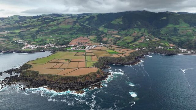 Terraced farmland meeting rugged basalt cliffs along Atlantic coastline of Sao Miguel, Azores, aerial view