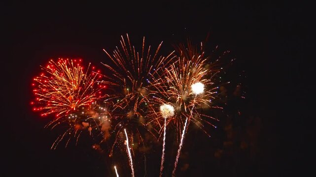 Colorful fireworks burst in the dark sky during a festival. The display takes place in a city, attracting many viewers. The night is filled with bright colors and loud sounds.
