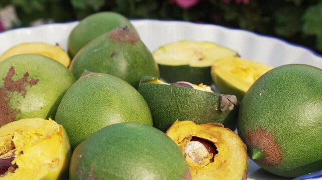 Fresh Whole and Sliced Peruvian Lucuma Fruit in a White Bowl