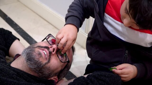 Kid playing to stick window christmas decoration on his father eyeglasses